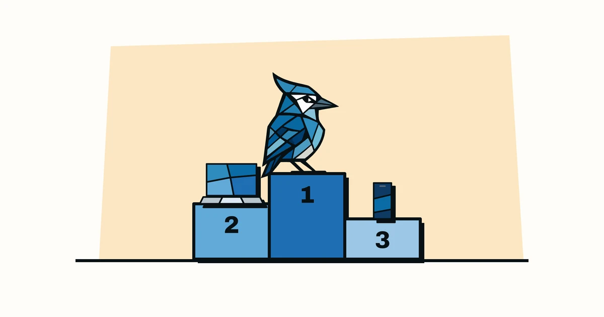 Jay the blue jay standing on the top step of a podium with a laptop and a phone on the lower steps