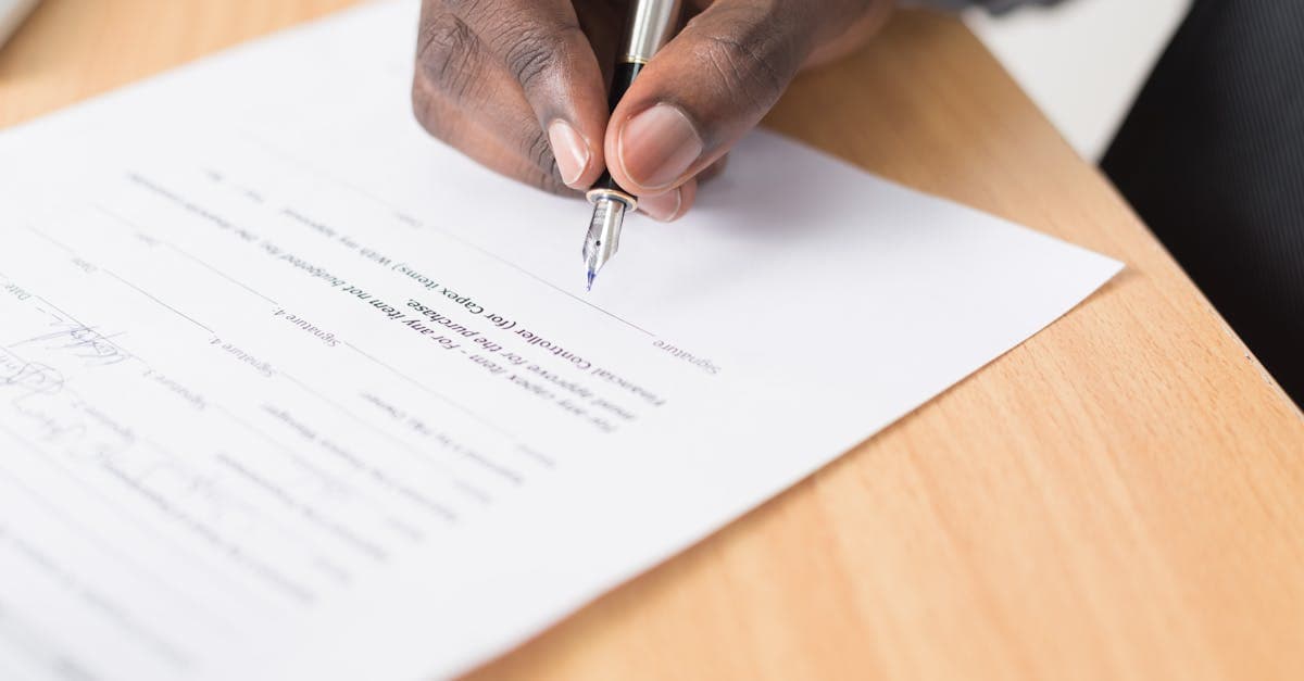 Person signing an equipment agreement document at a desk