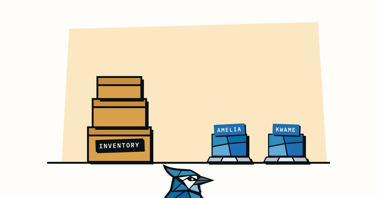 Jay the blue jay peeking up between stacked inventory boxes and laptops labelled with people's names